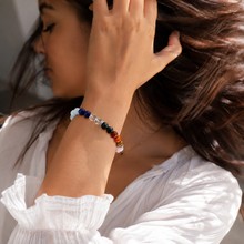 Load image into Gallery viewer, Model wearing MysticFlavia 7 Chakra bracelet on wrist while touching hair