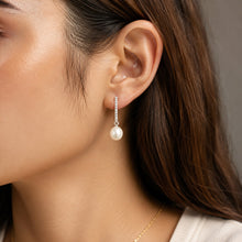 Load image into Gallery viewer, White pearl silver drop earring worn on a model’s ear, close-up