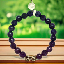 Load image into Gallery viewer, MysticFlavia amethyst round bead bracelet with silver charm on soft fabric background