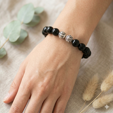 Load image into Gallery viewer, MysticFlavia black obsidian 925 sterling silver bead bracelet 12mm worn on wrist with dried flowers on linen surface