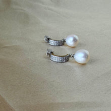 Load image into Gallery viewer, Elegant silver drop earrings featuring lustrous round white pearls on a soft textured surface.