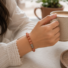 Load image into Gallery viewer, Female model wearing the Sunstone silver bead bracelet 8MM while holding a coffee mug in a cozy setting