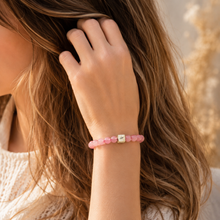 Load image into Gallery viewer, Woman wearing pink crystal bead bracelet with infinity cube charm in warm lifestyle portrait