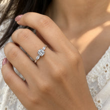 Load image into Gallery viewer, Model wearing a delicate floral moissanite ring with a round center stone and side accents