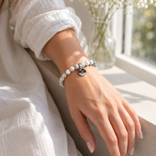 Load image into Gallery viewer, Woman wearing white howlite flat silver bead bracelet on wrist, bright window lifestyle shot