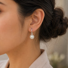 Load image into Gallery viewer, White pearl silver drop earrings shown in a close-up product view.