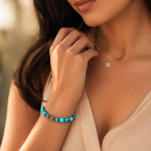 Load image into Gallery viewer, Natural turquoise round bracelet with carved silver beads worn on wrist, styled with delicate gold necklace, warm lifestyle shot