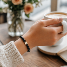 Load image into Gallery viewer, Woman wearing MysticFlavia black tourmaline bracelet on wrist while holding coffee cup, cosy lifestyle shot