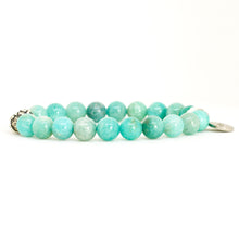 Load image into Gallery viewer, Side view of amazonite silver bead bracelet showing teal green beads with carved silver bead on left and round charm on right, white background