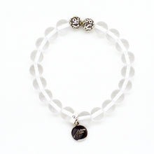 Load image into Gallery viewer, MysticFlavia clear quartz bracelet with two patterned silver beads and round brand charm pendant, flat lay on white