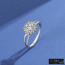 Load image into Gallery viewer, Moissanite silver ring with round center stone and floral halo design on a blue background