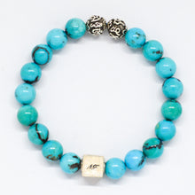 Load image into Gallery viewer, MysticFlavia turquoise infinity bracelet with bright blue beads, two carved silver beads on top and square brand tag at bottom, white background