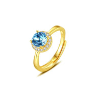 Blue gemstone gold ring with a round-cut center stone on a white background