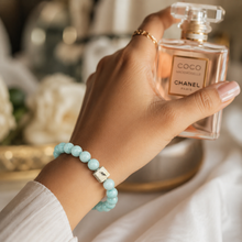 Load image into Gallery viewer, Amazonite round silver bracelet with pale teal beads and square MysticFlavia brand tag worn on wrist, glamour lifestyle shot

