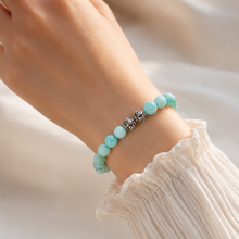 Load image into Gallery viewer, Natural amazonite infinity bracelet with 925 sterling silver carved beads worn on wrist, soft white fabric lifestyle shot

