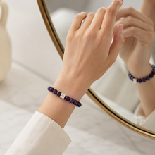 Load image into Gallery viewer, Woman wearing dark purple crystal bracelet beside mirror reflection in a bright indoor setting
