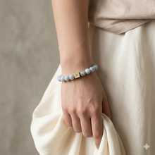 Load image into Gallery viewer, Natural aquamarine birthstone bracelet with silver infinity bead worn on wrist against draped white fabric, MysticFlavia lifestyle shot

