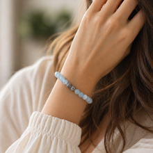 Load image into Gallery viewer, Aquamarine Birthstone round silver bracelet with pale blue beads and carved silver bead worn on wrist, soft indoor lifestyle shot

