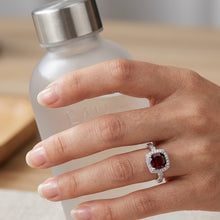 Load image into Gallery viewer, Red gemstone silver ring worn on a woman’s hand, showcasing the sparkling halo setting.
