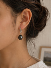 Load image into Gallery viewer, Black natural pearl silver drop earrings worn on a model’s ear
