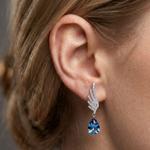 Load image into Gallery viewer, 1. Blue angel crystal dangling silver earrings worn on a model’s ear
