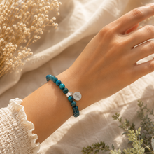 Load image into Gallery viewer, Woman wearing Blue Apatite Stone Flat Silver Bead Bracelet 8mm by MysticFlavia with natural blue apatite gemstone beads, flat 925 sterling silver bead, and logo charm.
