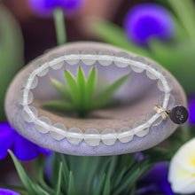 Load image into Gallery viewer, Clear quartz flat silver bead bracelet resting on a zen stone with succulents and blue flowers around it
