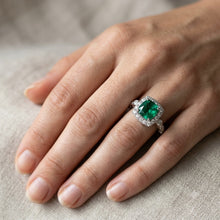Load image into Gallery viewer, Emerald silver ring worn on a woman's finger with sparkling halo setting
