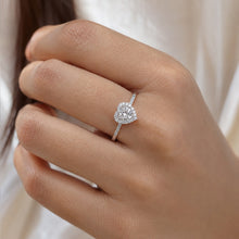Load image into Gallery viewer, Silver moissanite ring worn on a finger with a round center stone and halo setting
