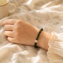Load image into Gallery viewer, Person wearing MysticFlavia Jade infinity bracelet with silver charm on wrist

