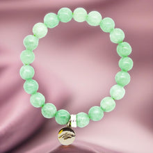 Load image into Gallery viewer, Jade bracelet close-up on soft background showing silver charm engraved with logo
