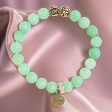 Load image into Gallery viewer, Jade bracelet close-up on soft fabric showing carved silver beads and round silver charm

