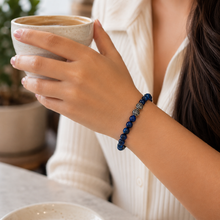 Load image into Gallery viewer, Female model wearing the Blue Kyanite infinity round silver bracelet 8mm while holding a coffee mug


