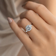 Load image into Gallery viewer, MysticFlavia moissanite halo ring worn on a hand with a sparkling round center stone
