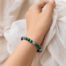 Load image into Gallery viewer, Person wearing MysticFlavia Malachite and Amethyst bracelet with carved silver beads on wrist
