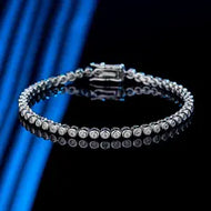 Moissanite tennis bracelet in silver, round stones set in a row, shown on blue background.
