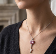Load image into Gallery viewer, Woman wearing Pink Crystal key pendant silver necklace with a pink heart crystal key pendant on a dark V-neck top
