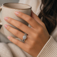 Load image into Gallery viewer, Moissanite halo ring worn on a woman's finger while holding a coffee mug
