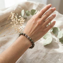 Load image into Gallery viewer, Hand wearing natural pyrite stone silver beads bracelet, soft botanical lifestyle shot


