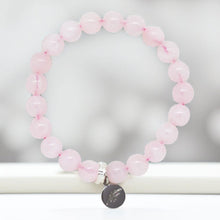 Load image into Gallery viewer, Rose quartz bracelet displayed upright with silver charm and soft blurred background
