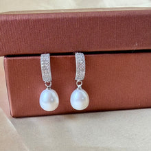 Load image into Gallery viewer, Silver pearl drop earrings displayed against a red jewelry box, highlighting the textured metal design.
