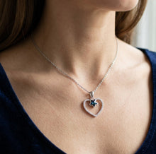 Load image into Gallery viewer, Woman wearing Star au Heart crystal silver necklace with open heart pendant on a dark V-neck top

