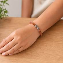 Load image into Gallery viewer, Female model wearing the Sunstone super silver bead bracelet 12mm on the wrist with a wooden table background


