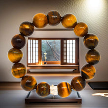 Load image into Gallery viewer, MysticFlavia tiger eye 12mm beaded bracelet displayed inside wooden frame, artistic styled shot
