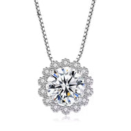 Moissanite pendant necklace in silver, round centre stone with flower-style halo border, on white background.
