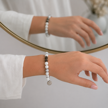 Load image into Gallery viewer, Woman wearing white howlite stone silver bead bracelet on wrist, mirror reflection lifestyle shot

