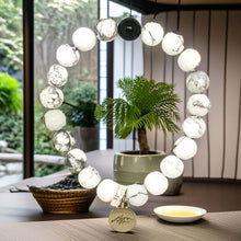 Load image into Gallery viewer, White Howlite and black bead bracelet hanging outdoors near a potted plant, MysticFlavia


