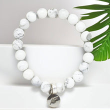 Load image into Gallery viewer, White howlite flat bracelet with 925 sterling silver charm, grey background with green leaf
