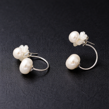 Load image into Gallery viewer, White pearl flower hoop earrings on a dark background
