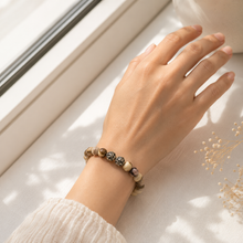 Load image into Gallery viewer, Female model wearing Australian Zebra Stone Silver Bead Bracelet 8mm with 925 Sterling Silver Om beads in natural window light.
